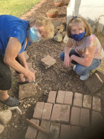Mrs. Riddlesperger and Abi make a brick path.